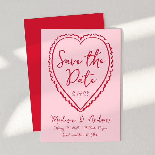 Pink 'Save the Date' card with red heart design on a gray background