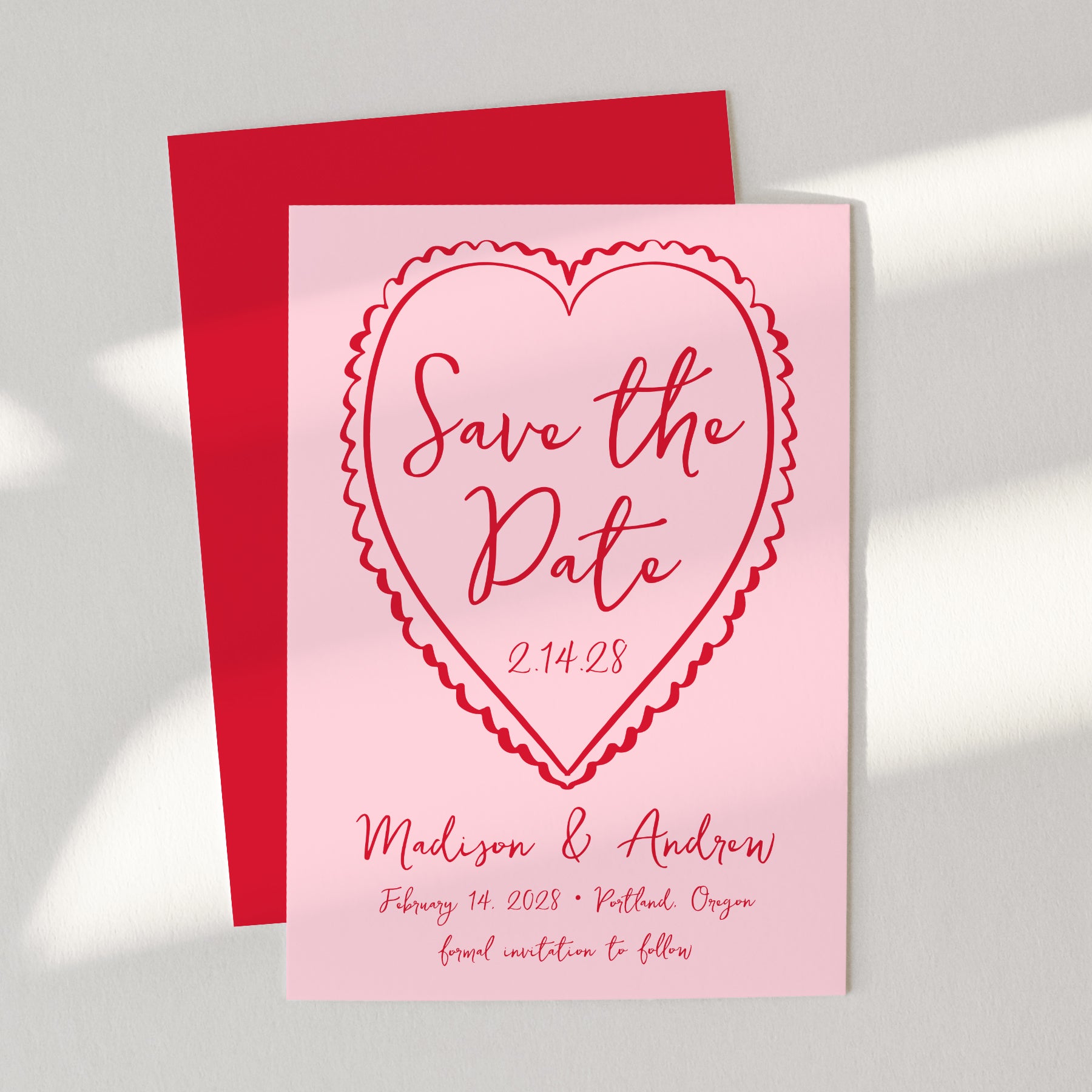 Pink 'Save the Date' card with red heart design on a gray background