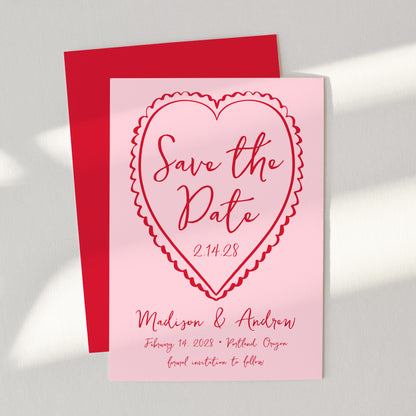 Pink 'Save the Date' card with red heart design on a gray background